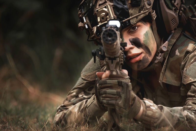 A player in camouflage taking aim while lying prone